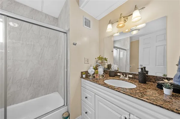 a bathroom with a granite countertop sink a mirror and a shower