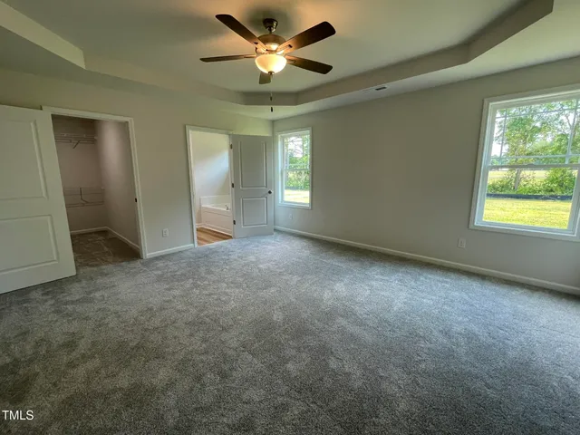 a view of an empty room with window and chandelier fan