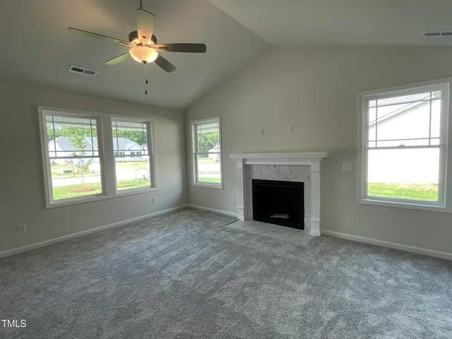 an empty room with windows and fireplace