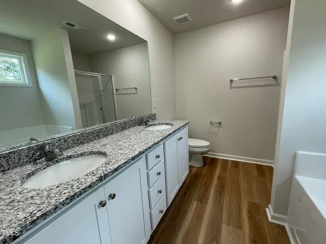 a bathroom with a granite countertop sink a large mirror a toilet and a bathtub