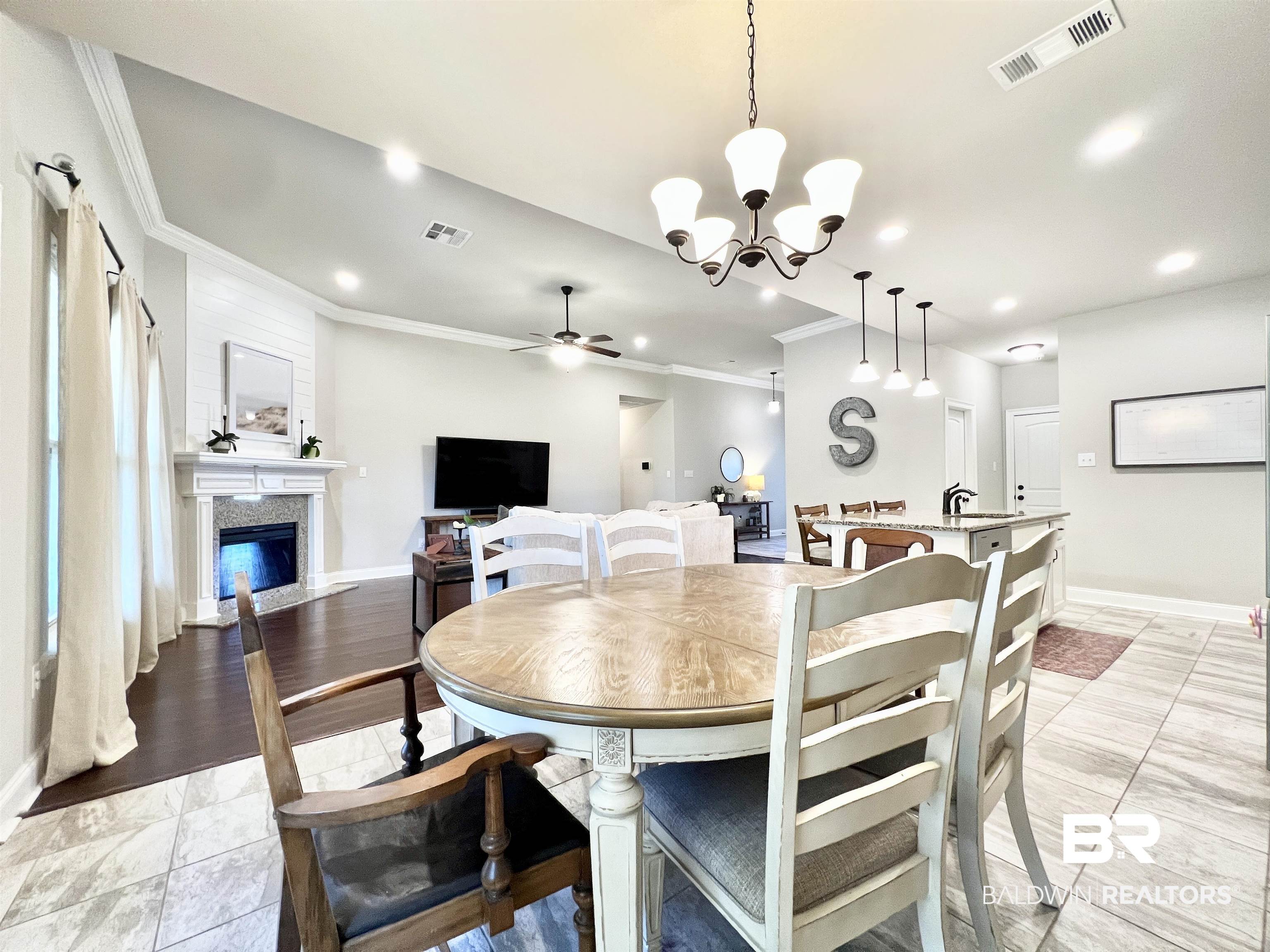 32290 Calder Court Daphne, AL 36527 - Photo 15 of 59 Dining area with a premium fireplace, light hardwood / wood-style flooring, ceiling fan with notable chandelier, and crown molding
