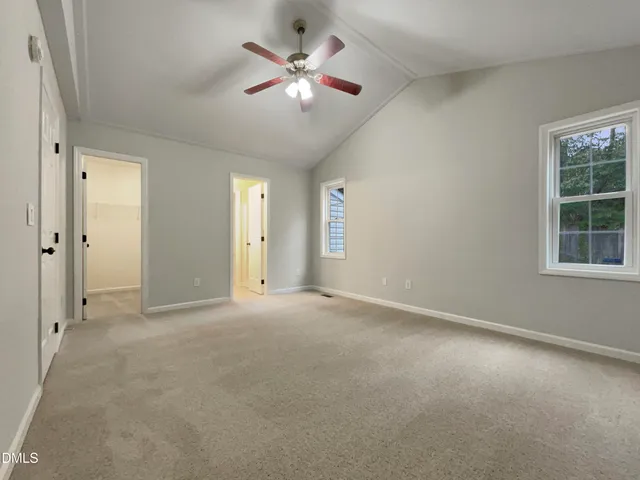 an empty room with chandelier fan and windows