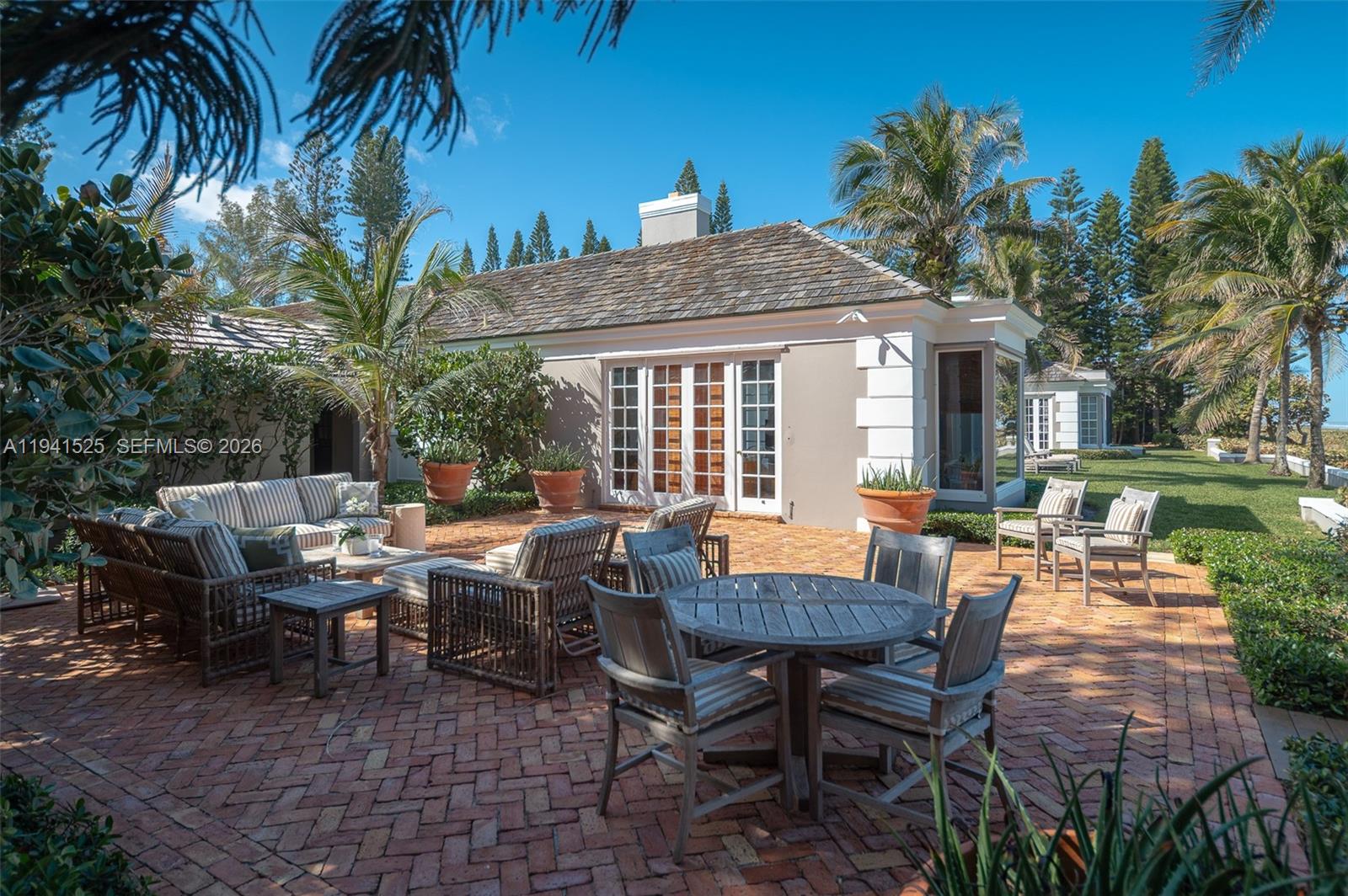 21 South Beach Road Jupiter Island, FL 33455 - Photo 34 of 45 a view of a patio with table and chairs potted plants and a palm tree