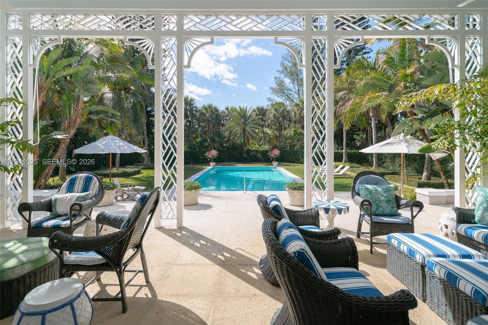 21 South Beach Road Jupiter Island, FL 33455 - Photo 7 of 45 a view of a patio with couches table and chairs under an umbrella with a garden