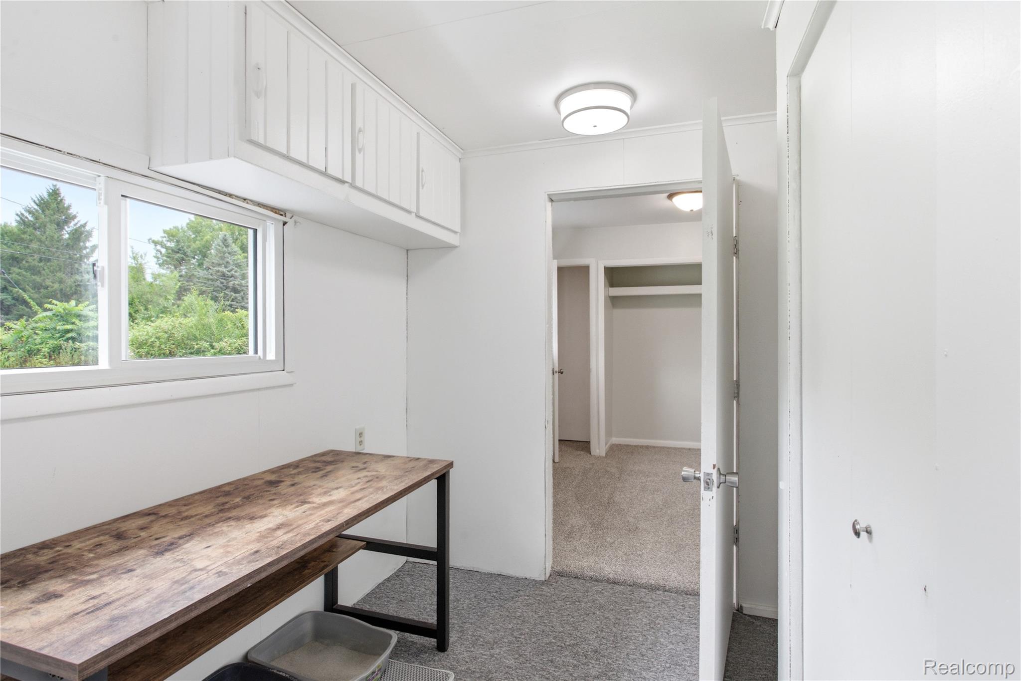 4945 Miller Road Ann Arbor, MI 48103 - Photo 18 of 42 White upper cabinetry, double pane window, wood-finish console, flush mount lighting, and carpeted flooring
