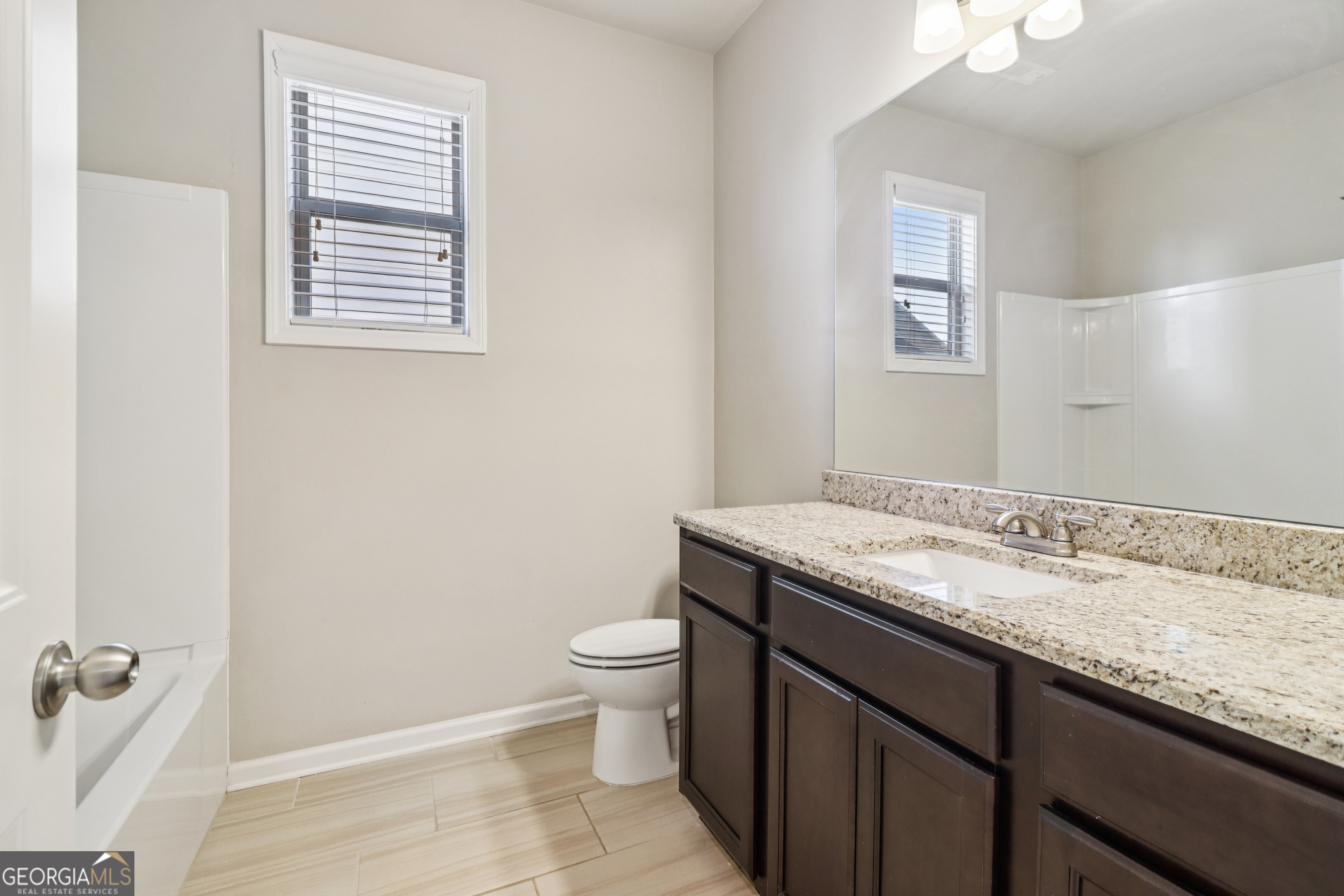 7671 Silk Tree Braselton, GA 30517 - Photo 30 of 92 a bathroom with a granite countertop sink a toilet and a mirror