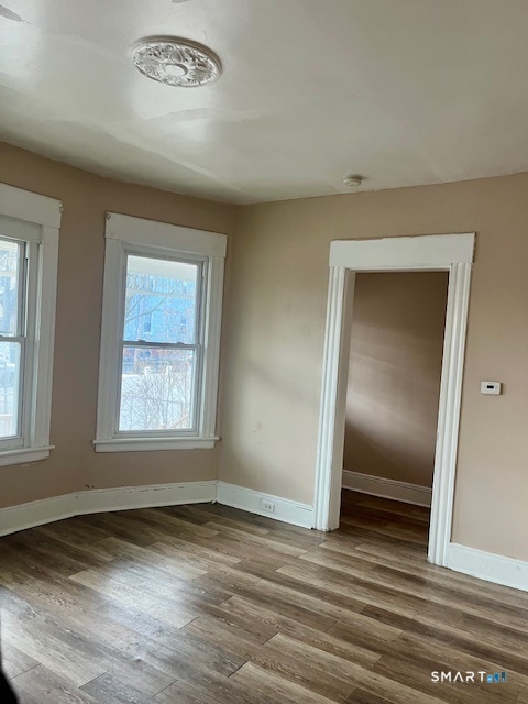 166 Laurel Avenue Bridgeport, CT 06605 - Photo 4 of 15 an empty room with wooden floor and windows