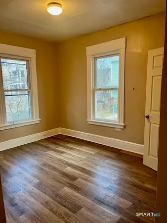 a view of an empty room with wooden floor and a window