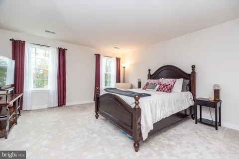 a bedroom with a bed and a flat tv screen on dresser