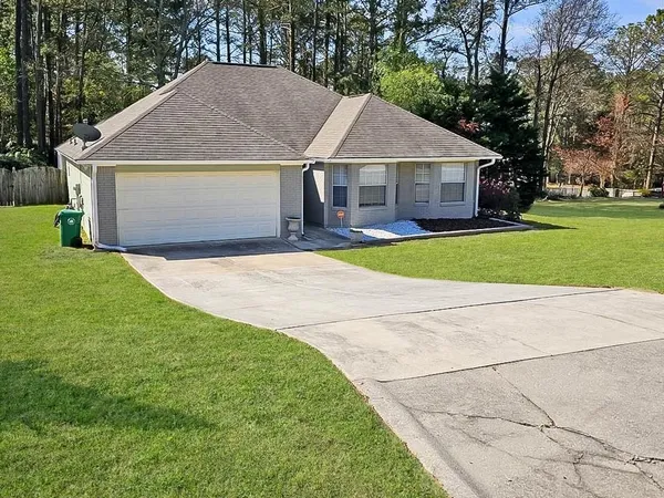 a front view of a house with a garden and trees