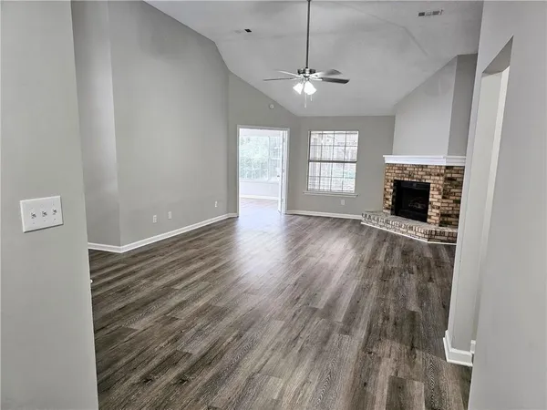an empty room with wooden floor fireplace and windows