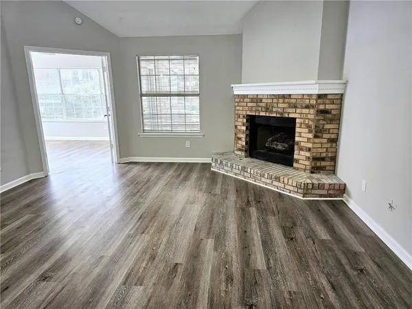 an empty room with wooden floor a fireplace and windows