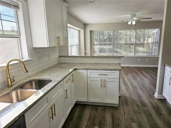 a kitchen with granite countertop white cabinets and a sink