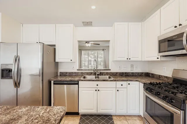 a kitchen with granite countertop a sink stainless steel appliances and white cabinets