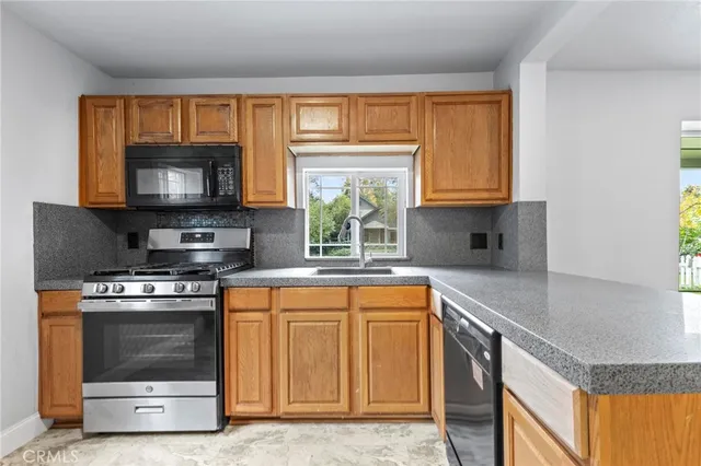 a kitchen with stainless steel appliances granite countertop a stove a sink and a microwave