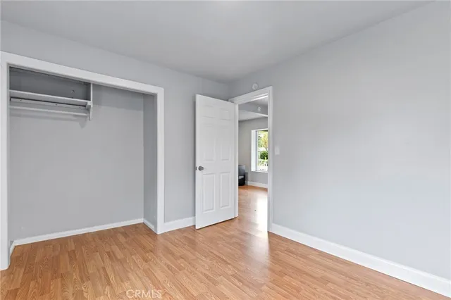 a view of an empty room with wooden floor and closet