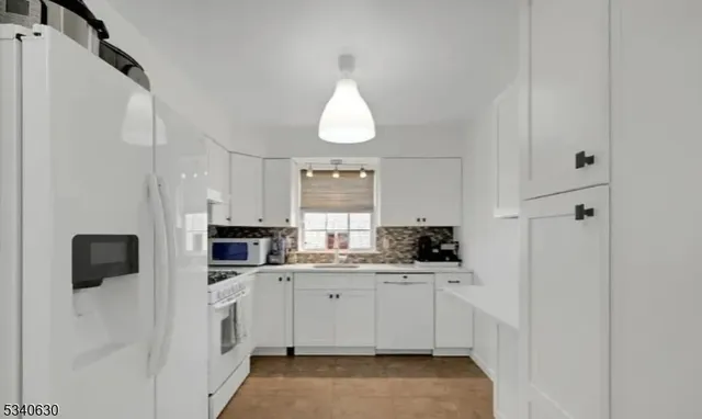 a kitchen with white cabinets and white appliances
