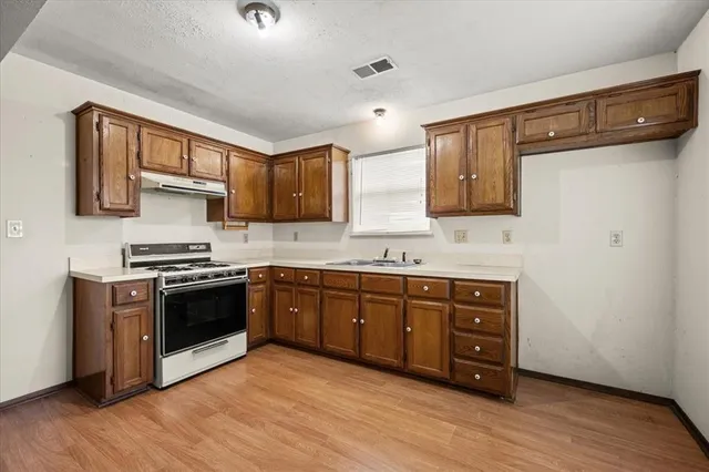a kitchen with stainless steel appliances granite countertop a stove a sink and a refrigerator