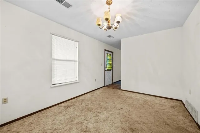 a view of an empty room with window and chandelier fan