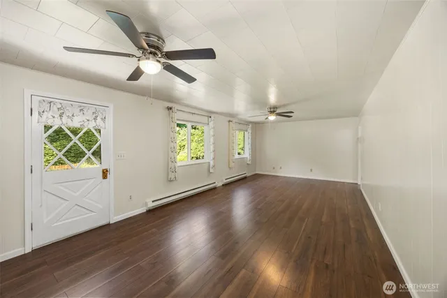 an empty room with wooden floor fan and windows