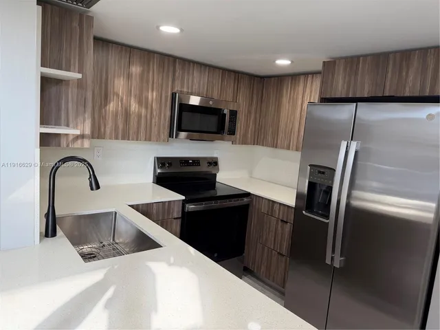 a kitchen with stainless steel appliances wooden cabinets a refrigerator and a sink