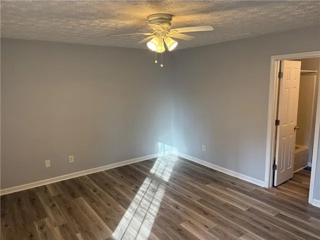 an empty room with wooden floor closet and windows
