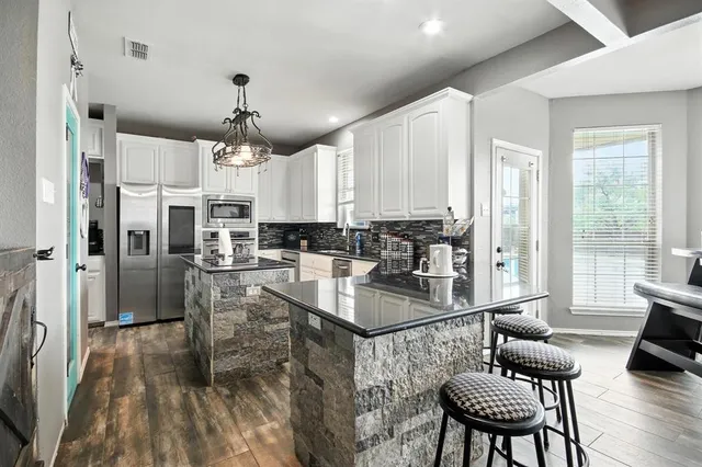 a kitchen with stainless steel appliances granite countertop a stove refrigerator a dining table and chairs with wooden floor