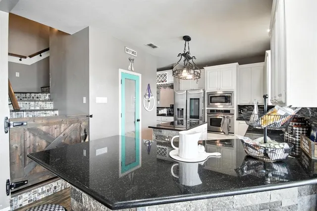 a kitchen with stainless steel appliances kitchen island granite countertop a refrigerator and cabinets