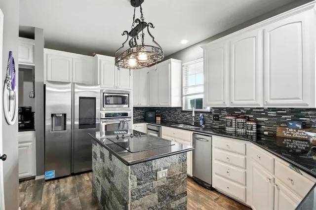 a kitchen with stainless steel appliances granite countertop a sink a stove a refrigerator cabinets and chairs