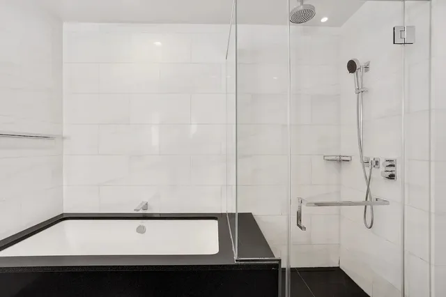 a bathroom with a sink double vanity granite tub shower and a mirror