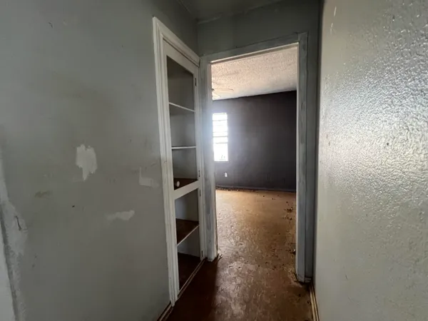 a view of a hallway with wooden floor and a living room