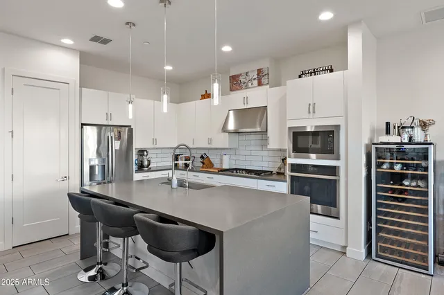 a kitchen with stainless steel appliances a refrigerator a stove a sink a dining table and chairs