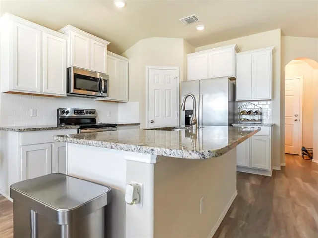 a kitchen with stainless steel appliances granite countertop a sink refrigerator and microwave