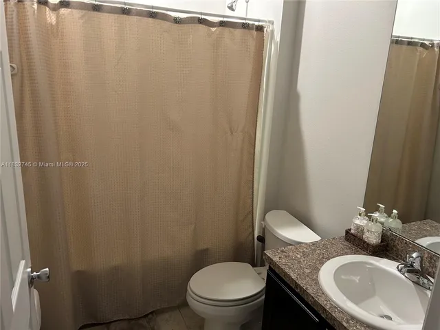 a bathroom with a granite countertop sink toilet and a mirror