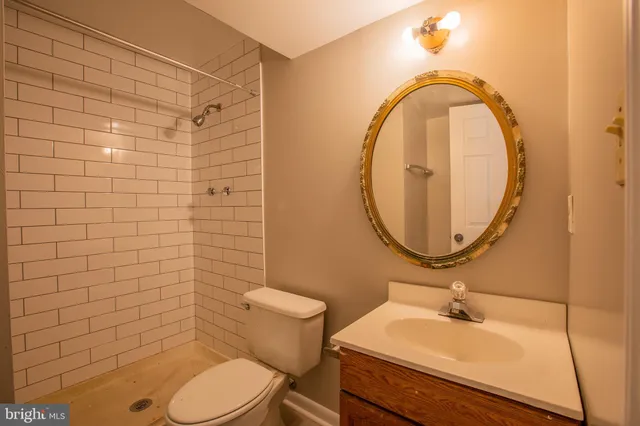 a bathroom with a granite countertop sink a toilet and shower