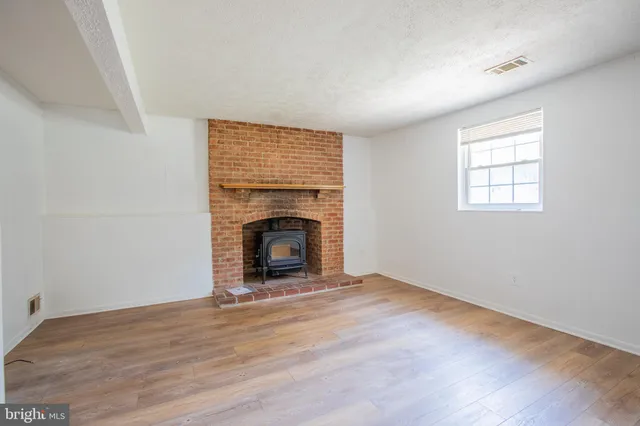an empty room with wooden floor a fireplace and windows