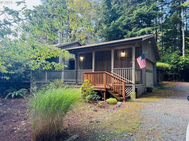 a view of a wooden house with a small yard plants and large trees
