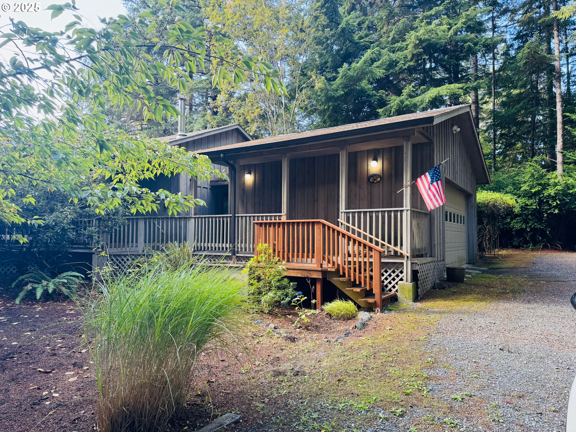 88468 Trout Pond Lane Southwest Bandon, OR 97411 - Photo 1 of 44 a view of a wooden house with a small yard plants and large trees
