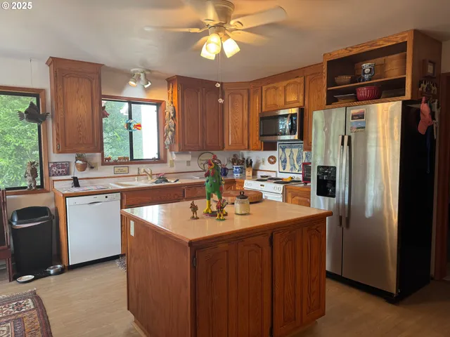 a kitchen with stainless steel appliances granite countertop a sink a stove a refrigerator cabinets and a dining table