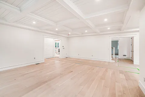 an empty room with wooden floor and natural light