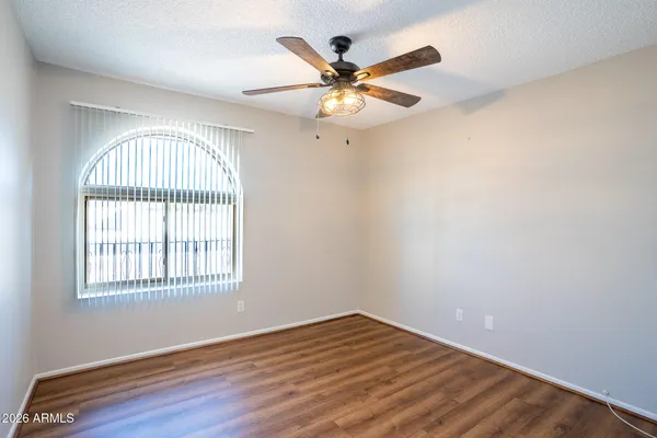 an empty room with wooden floor fan and windows