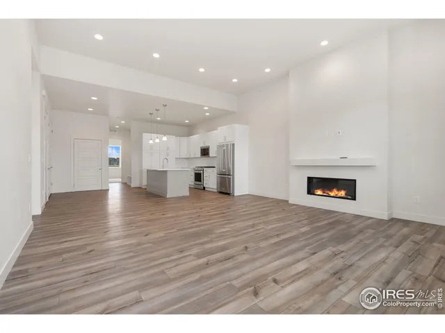 a view of an empty room and a kitchen
