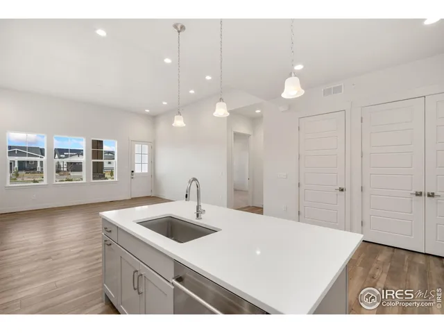 a kitchen with a sink chandelier and wooden floor