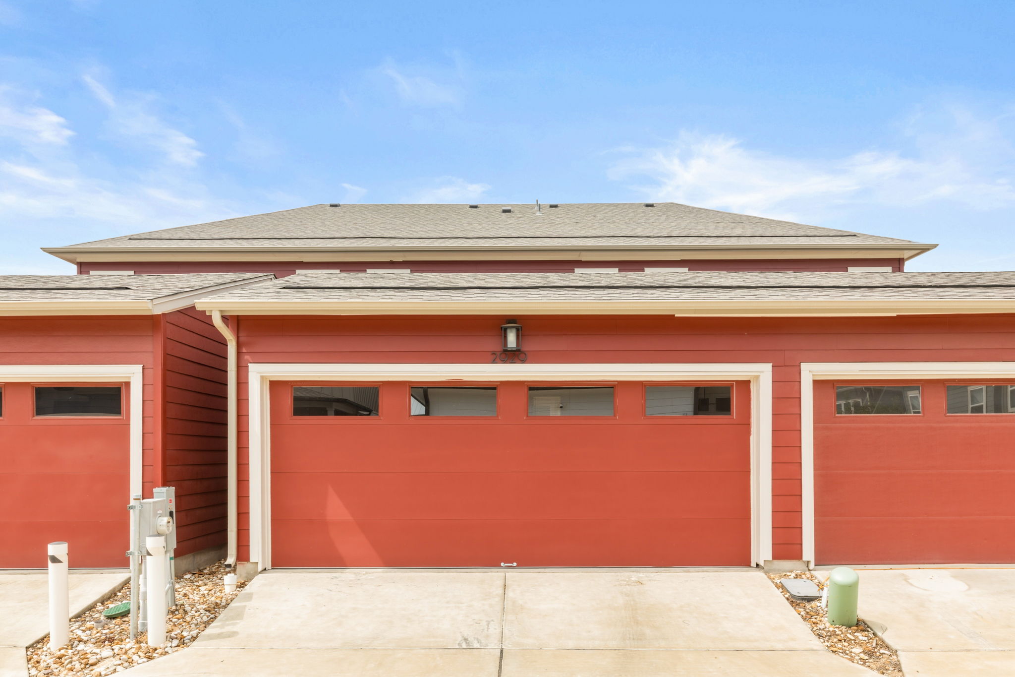 2929 Moreno Street Austin, TX 78723 - Photo 40 of 40 Attached dual garage doors with upper window panels, set against a red siding facade with white trim