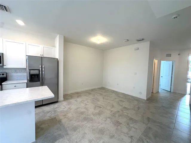 a view of a refrigerator in kitchen and empty room