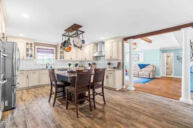 a view of dining room and livingroom with furniture wooden floor a rug a painting and a chandelier