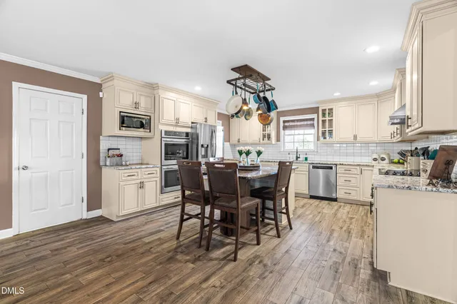 a kitchen with stainless steel appliances kitchen island wooden floors and white cabinets