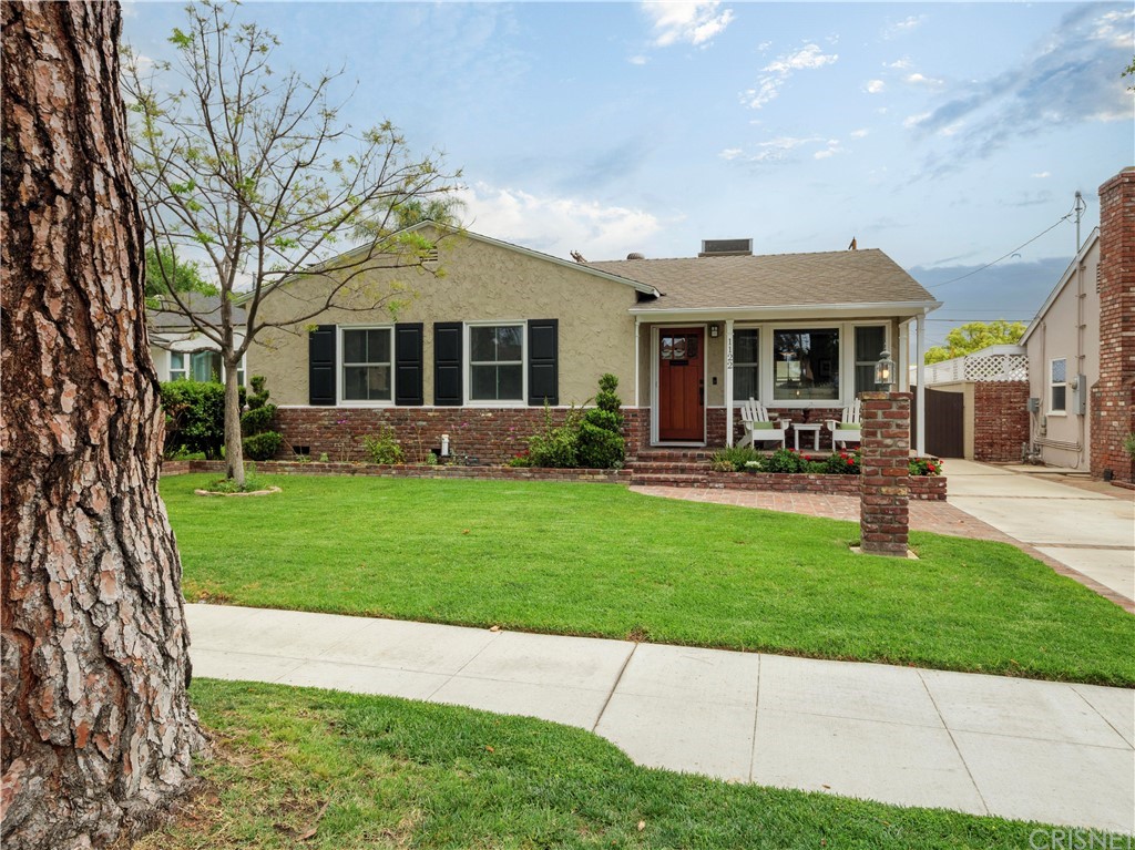 a front view of a house with a garden and trees