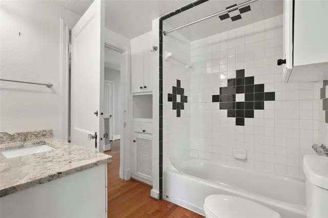 a bathroom with a granite countertop sink a toilet and shower