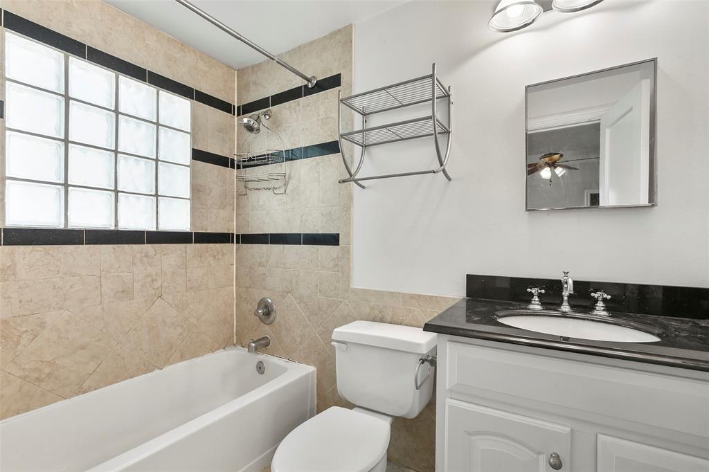 6166 Oram Street Dallas, TX 75214 - Photo 24 of 25 a bathroom with a granite countertop sink a toilet a mirror and shower